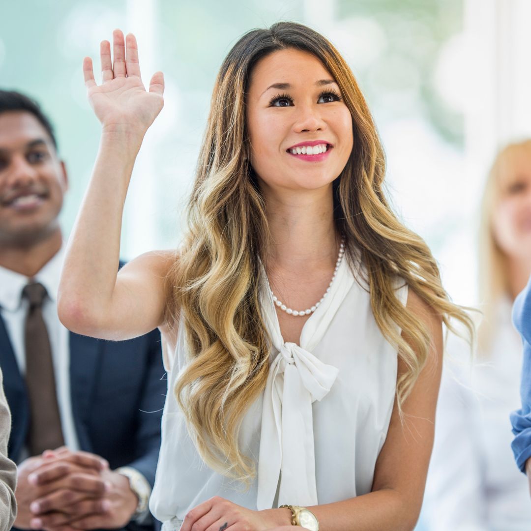 A woman raises her hand to ask a question.