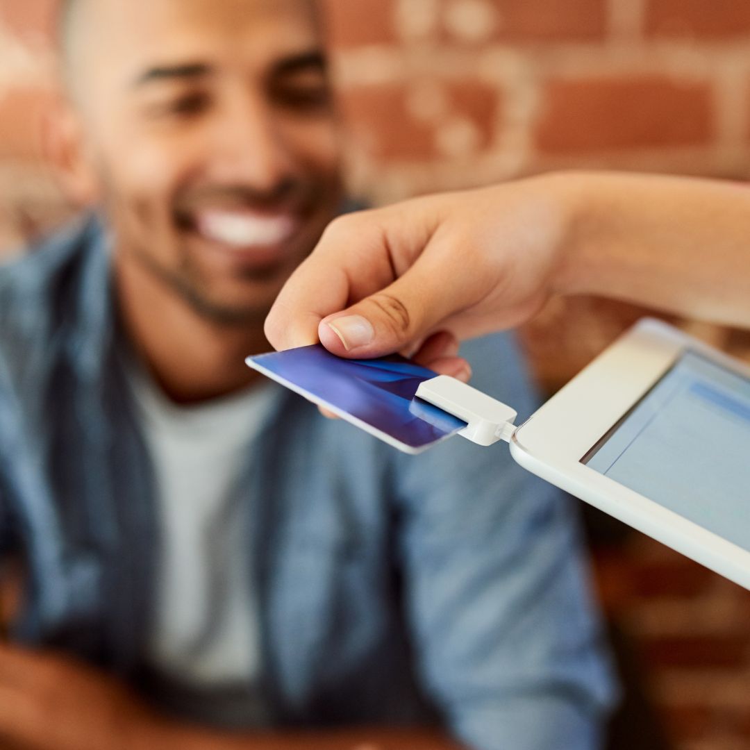 A business representative swipes a client's card to process a payment.